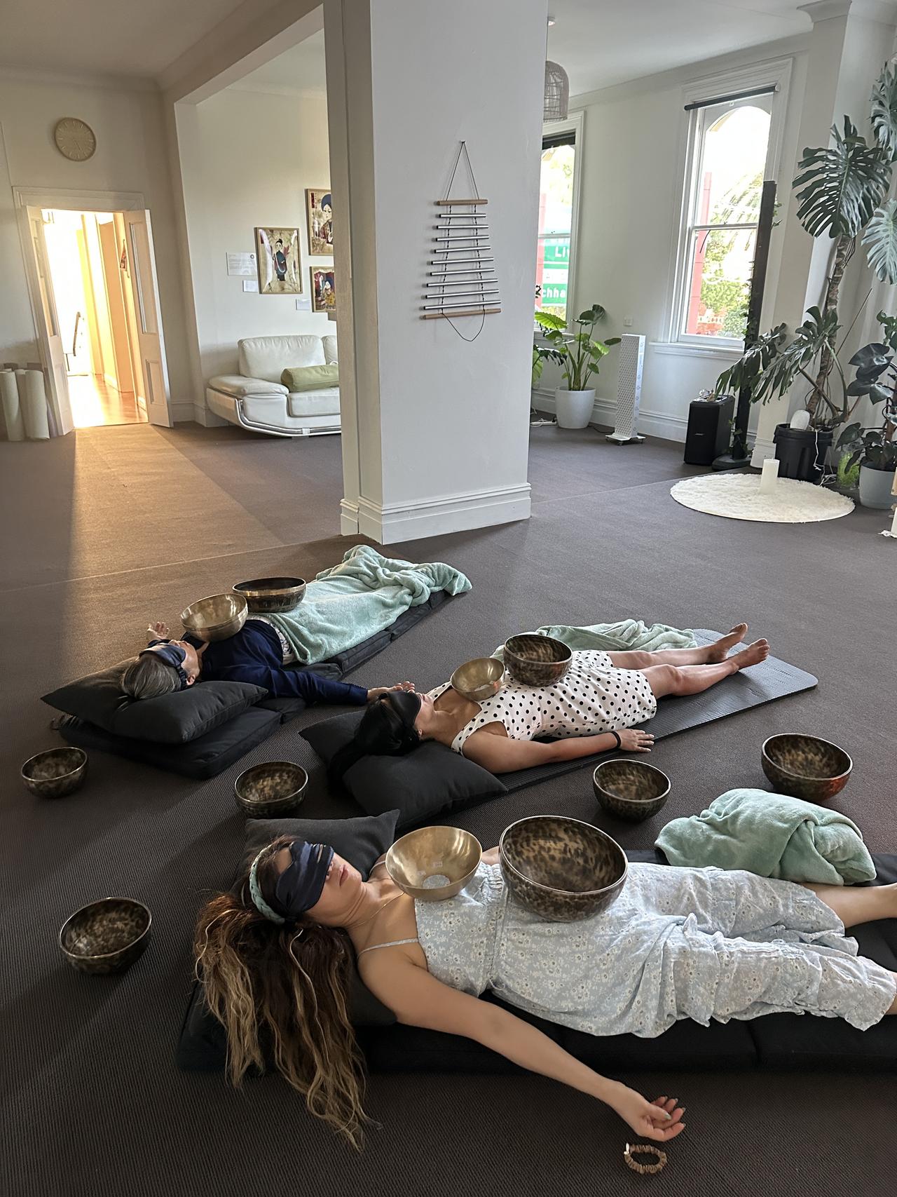 Tibetan singing bowls placed on a client during a private vibrational massage session at Mystic Wellness Petersham